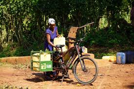 "A young Kenyan using an electric bike in a rural setting, blending modern e-mobility with traditional Indigenous practices and sustainable living."